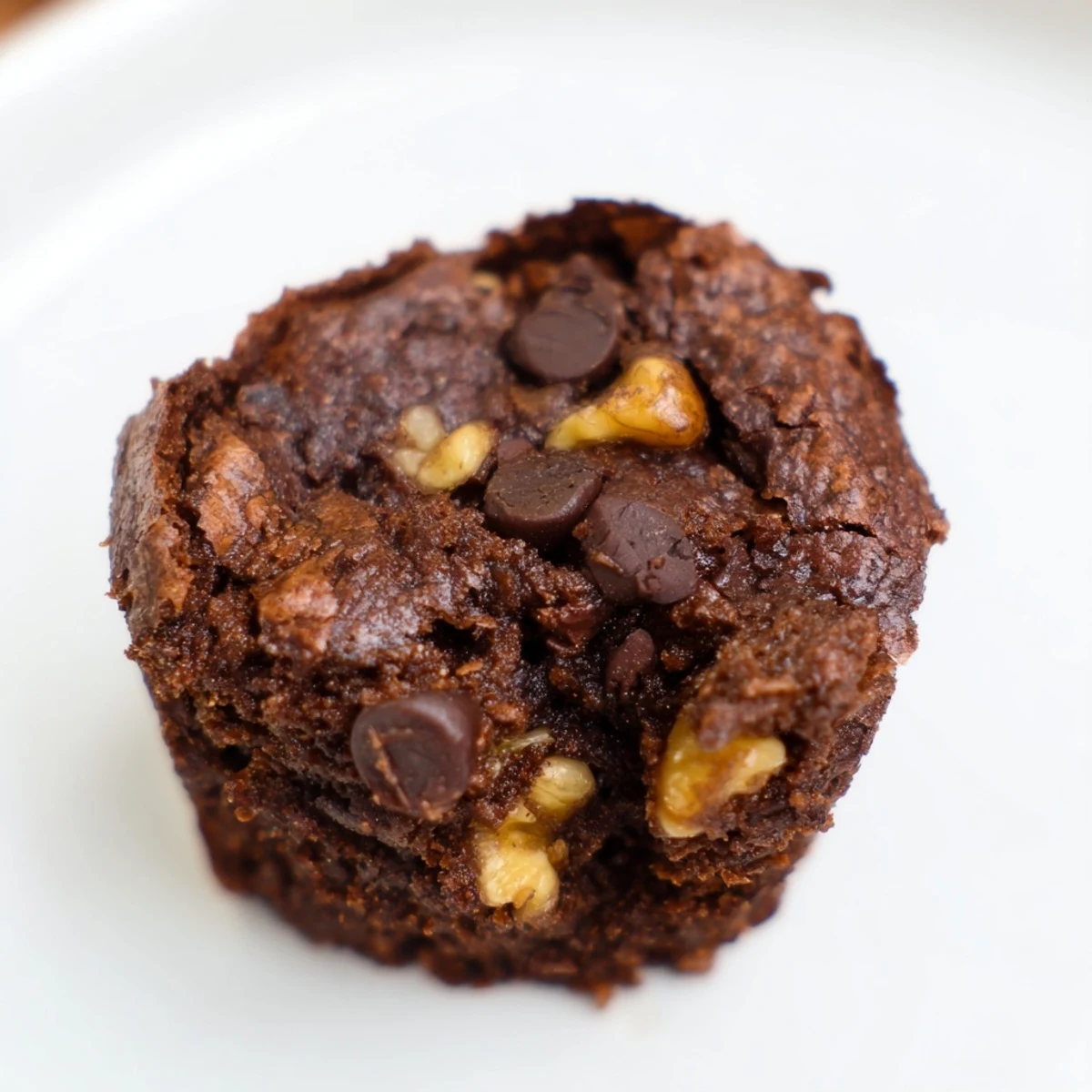 A batch of freshly baked Chocolate Brownie Bites in a mini muffin pan, featuring cracked tops and visible chocolate chips.