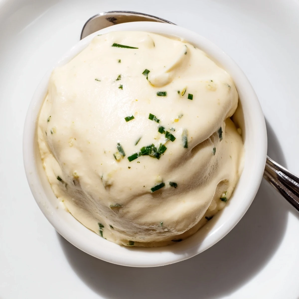 A small bowl of Creamy Salad Dressing surrounded by fresh vegetable crudités for dipping, on a rustic table.