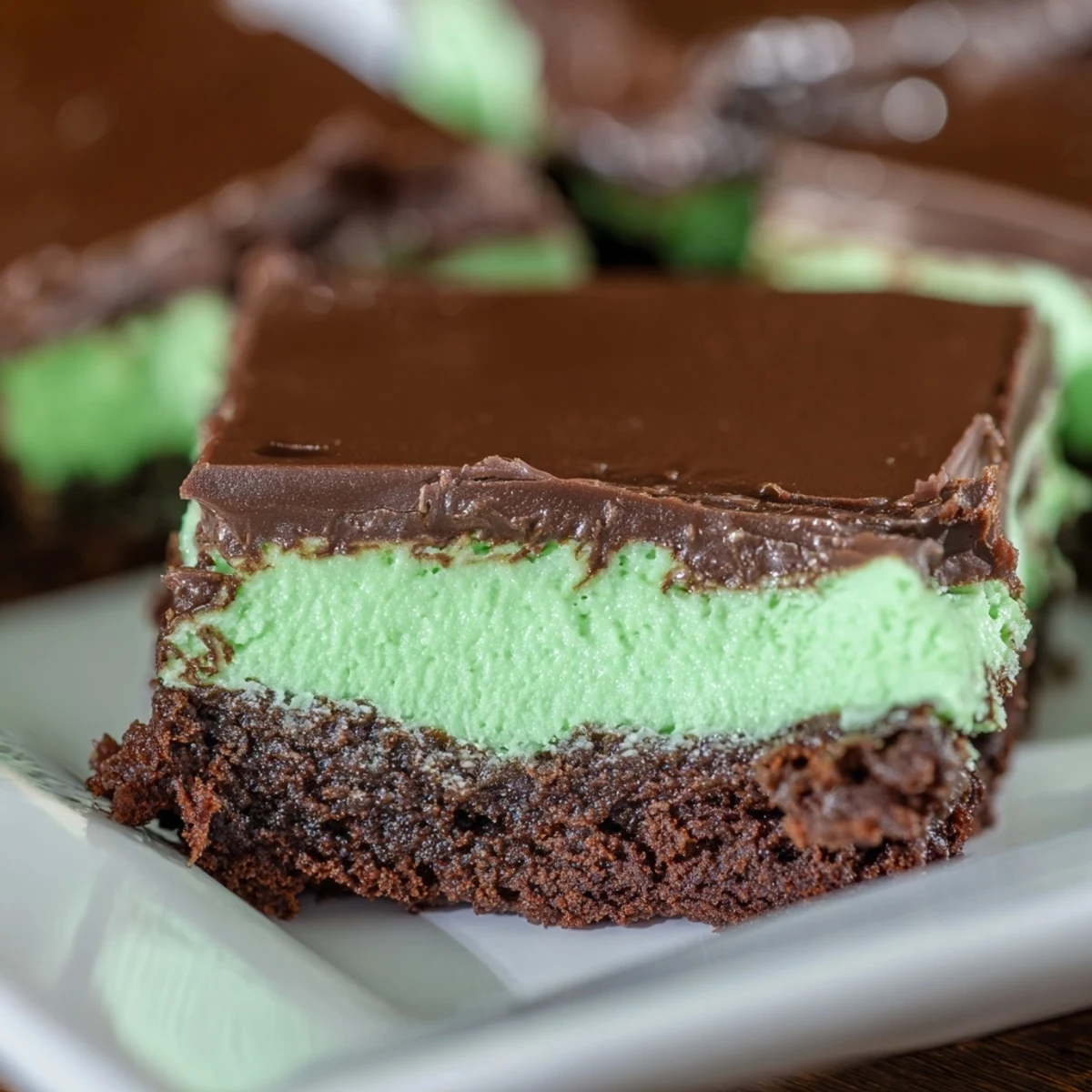 St. Patricks Day Mint Brownies sit on a white plate with a glass of milk, perfect for a festive dessert spread.