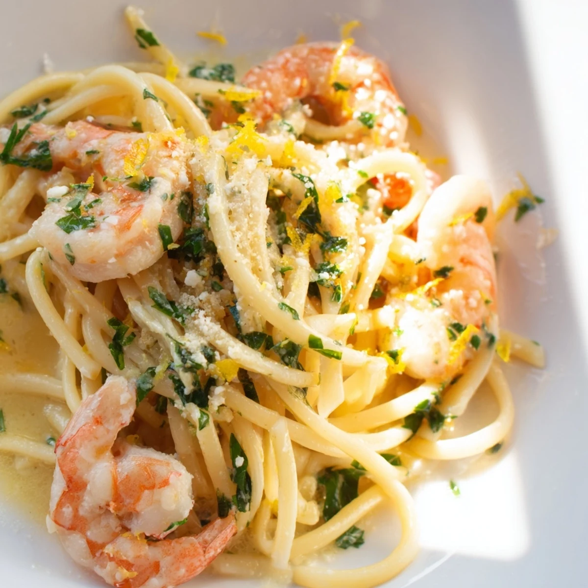 Parsley and lemon zest garnish Romantic Shrimp Scampi with Linguine served with a glass of white wine.