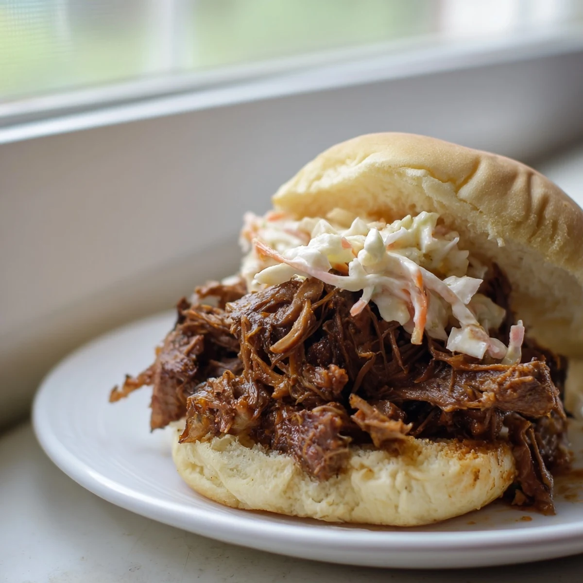 Tender shreds of Slow Cooked Pulled Beef Sandwiches on a toasted bun, with a side of potato wedges and amber ale.