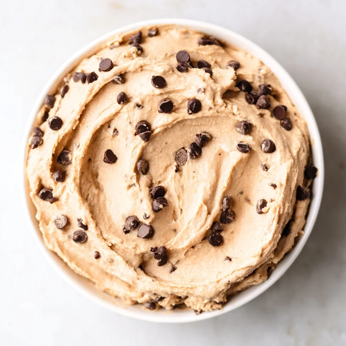Visually appealing Chocolate Chip Cookie Dough Hummus served in a rustic bowl alongside crunchy pretzels.
