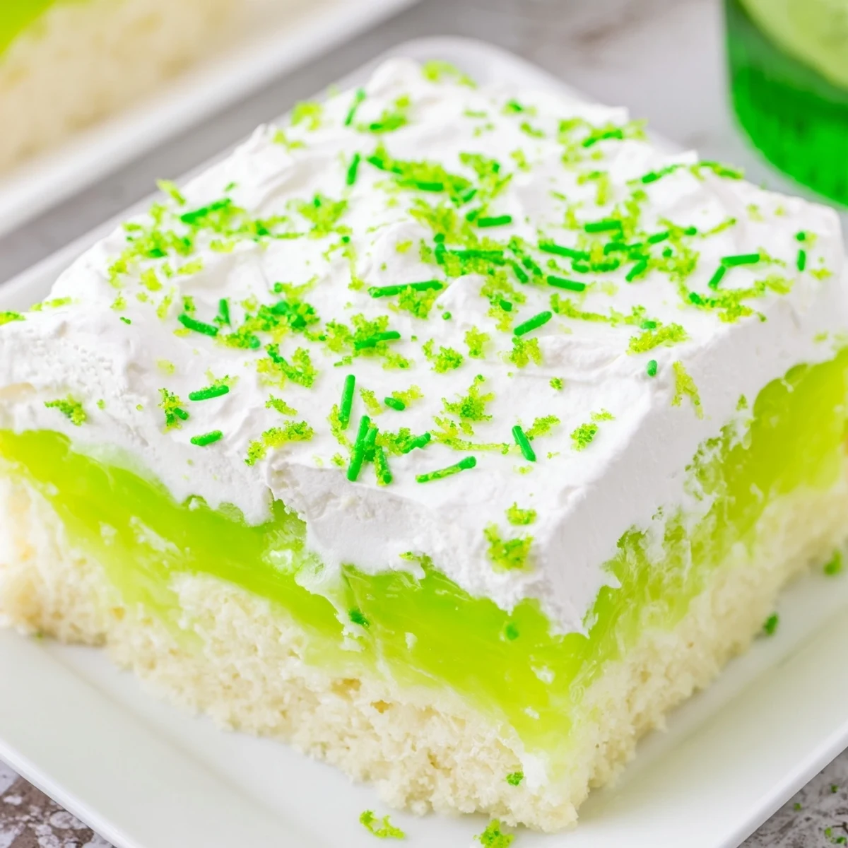 Festive St. Patricks Day Lime Poke Cake on a wooden table with lime zest garnish and bright colors.