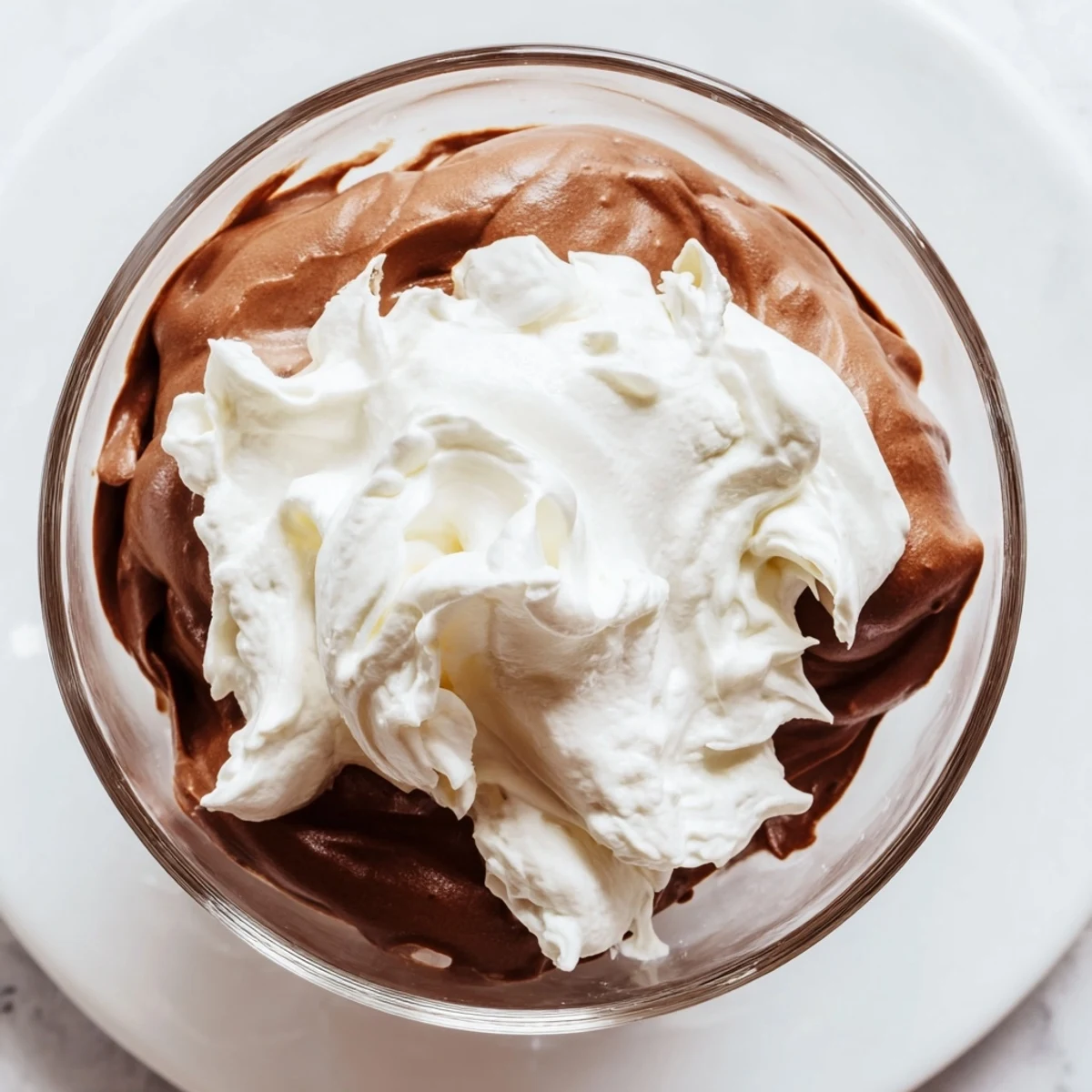 Chocolate mousse in a dessert glass, airy texture, smooth whipped cream, and a rustic chocolate garnish.