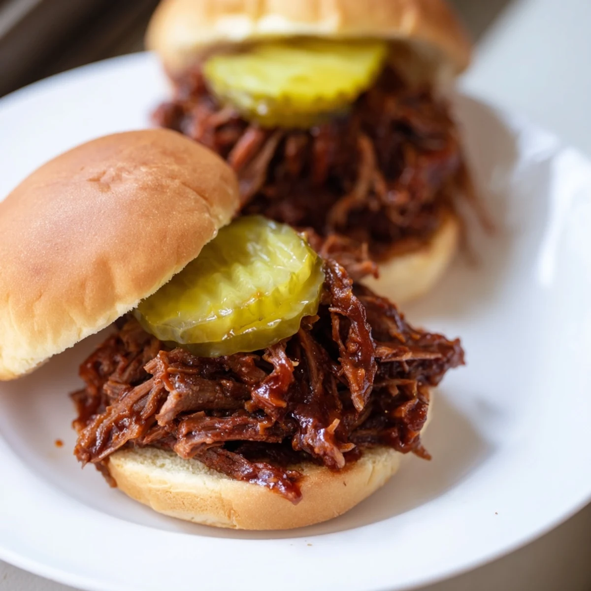 Homemade pulled beef sliders served on a rustic board, featuring juicy meat and pickle toppings for a classic American treat.