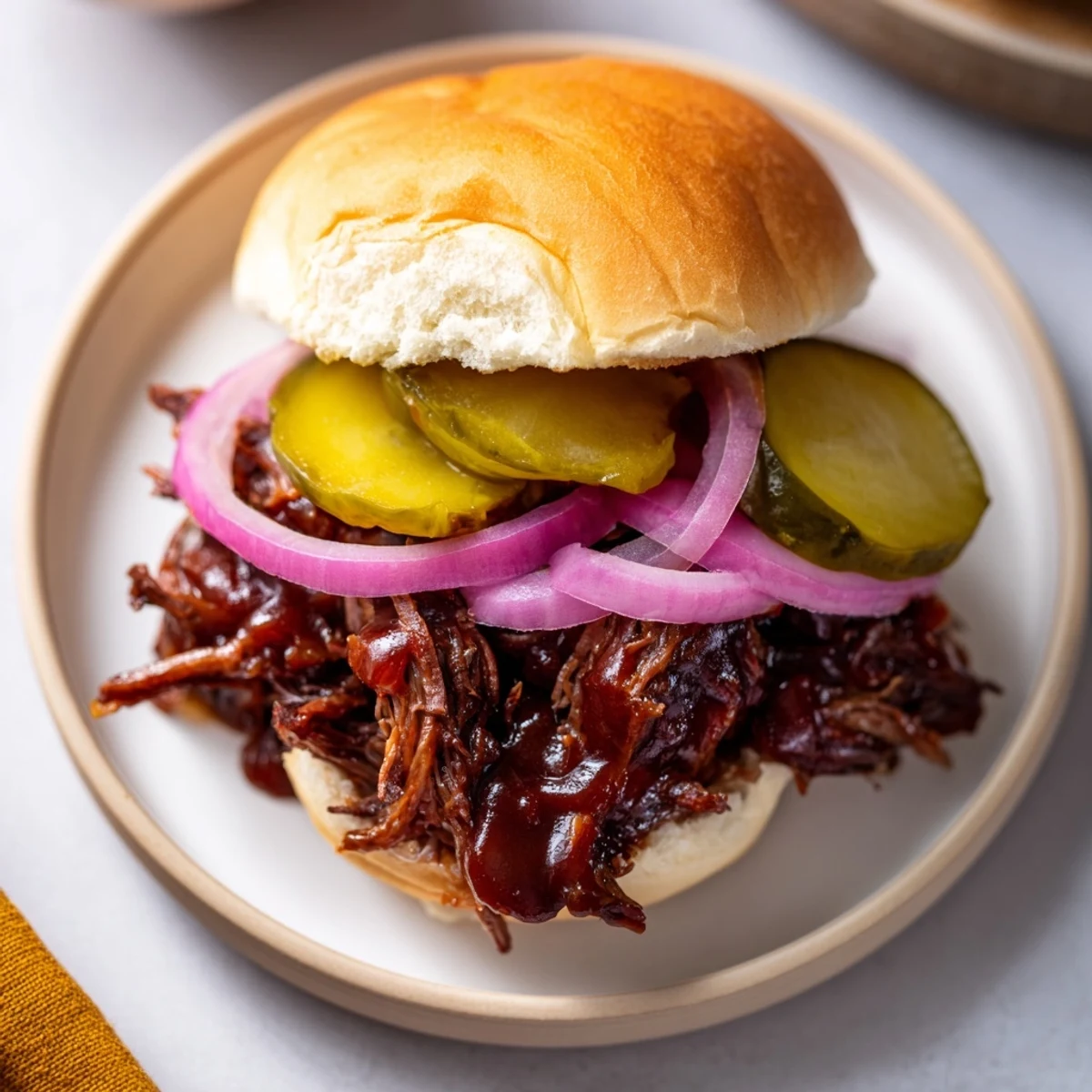 Slow-cooked, shredded beef stacked on buttery slider buns with tangy dill pickles and crisp red onion slices for a satisfying bite.