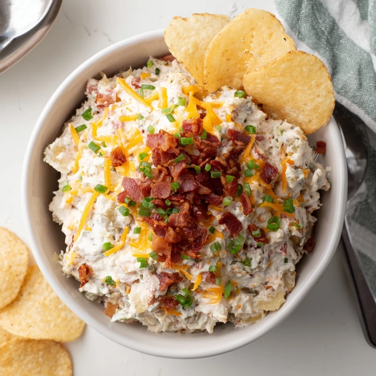 Hearty Loaded Baked Potato Dip in a bowl, bacon and chive garnish, thick-cut potato chips for scooping.