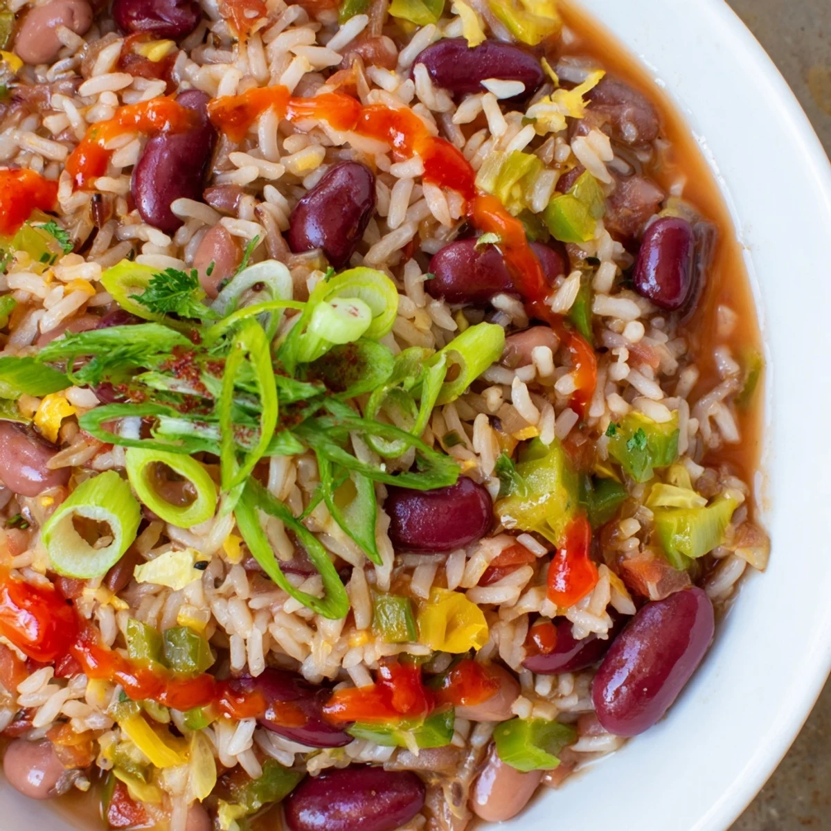 A vibrant bowl of Mardi Gras Rice and Beans, garnished with fresh green onions and parsley, ready to celebrate.
