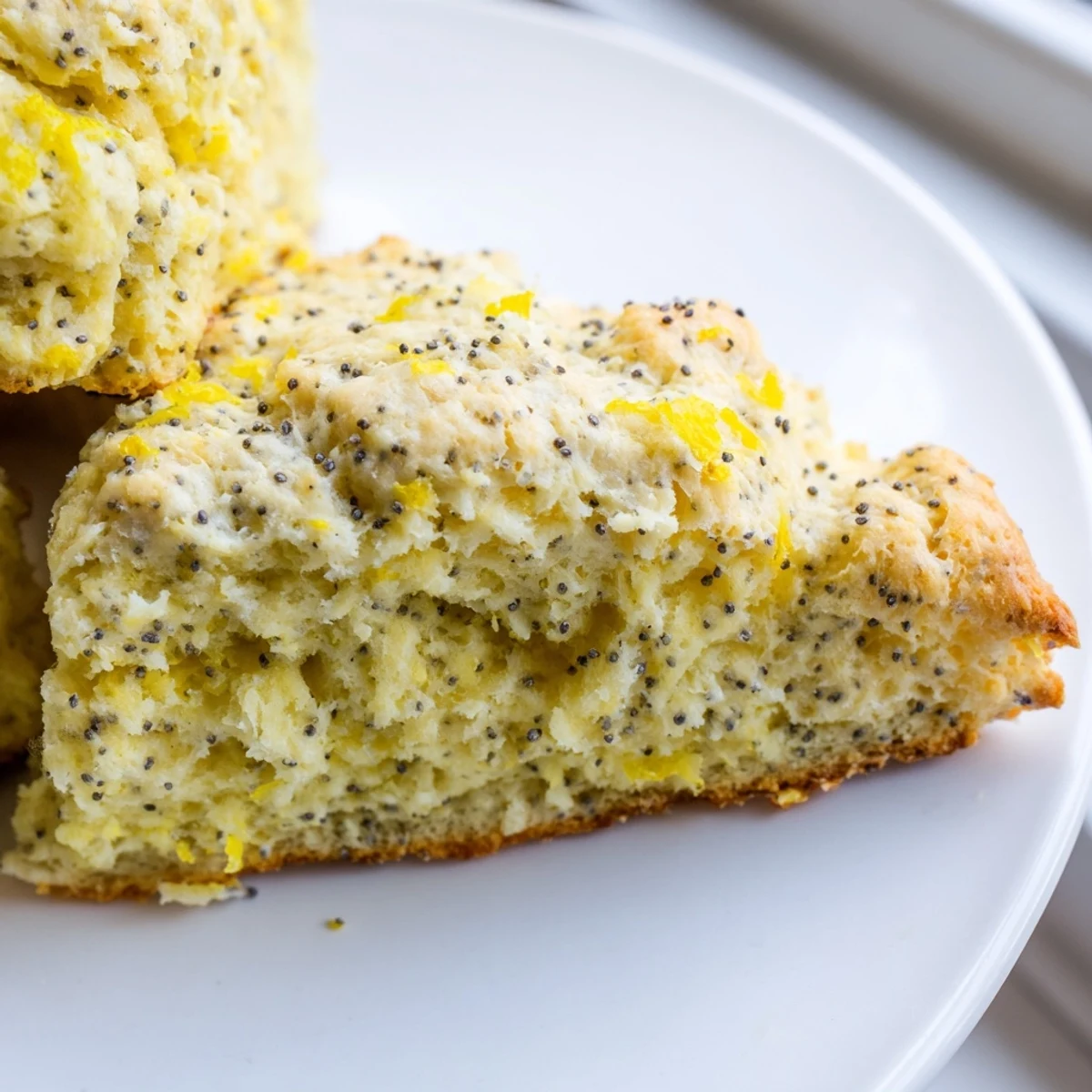 Golden Lemon Poppy Seed Scones fresh from the oven, drizzled with sweet glaze and served on a rustic plate.