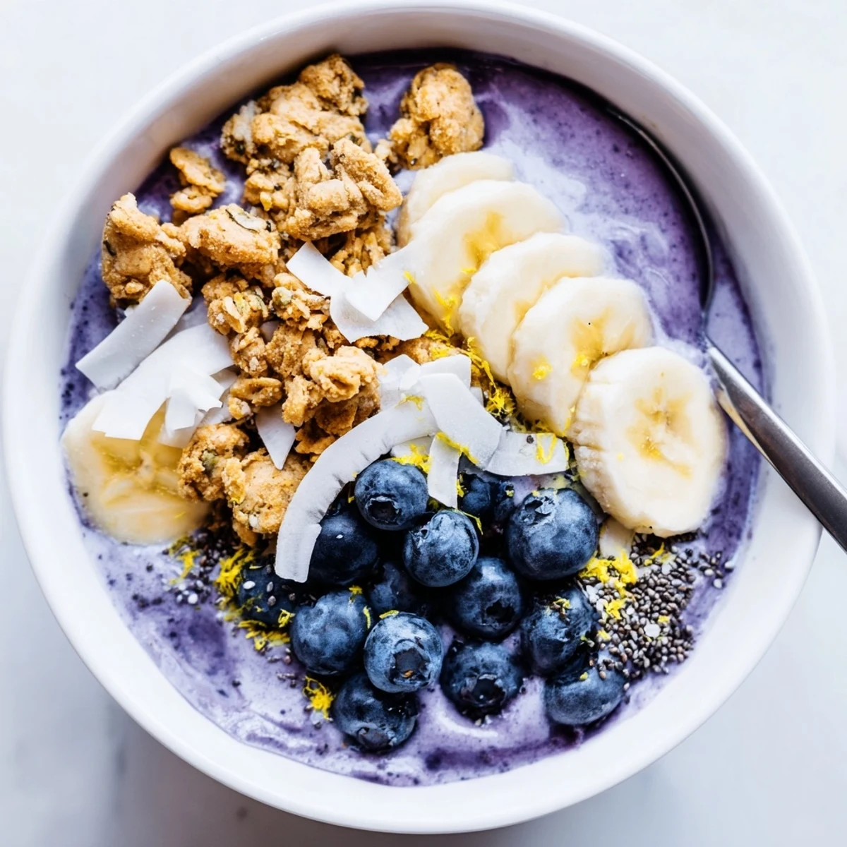 Close-up of Lemon Blueberry Smoothie Bowl with granola, chia seeds, and coconut flakes garnish for a nutritious snack.