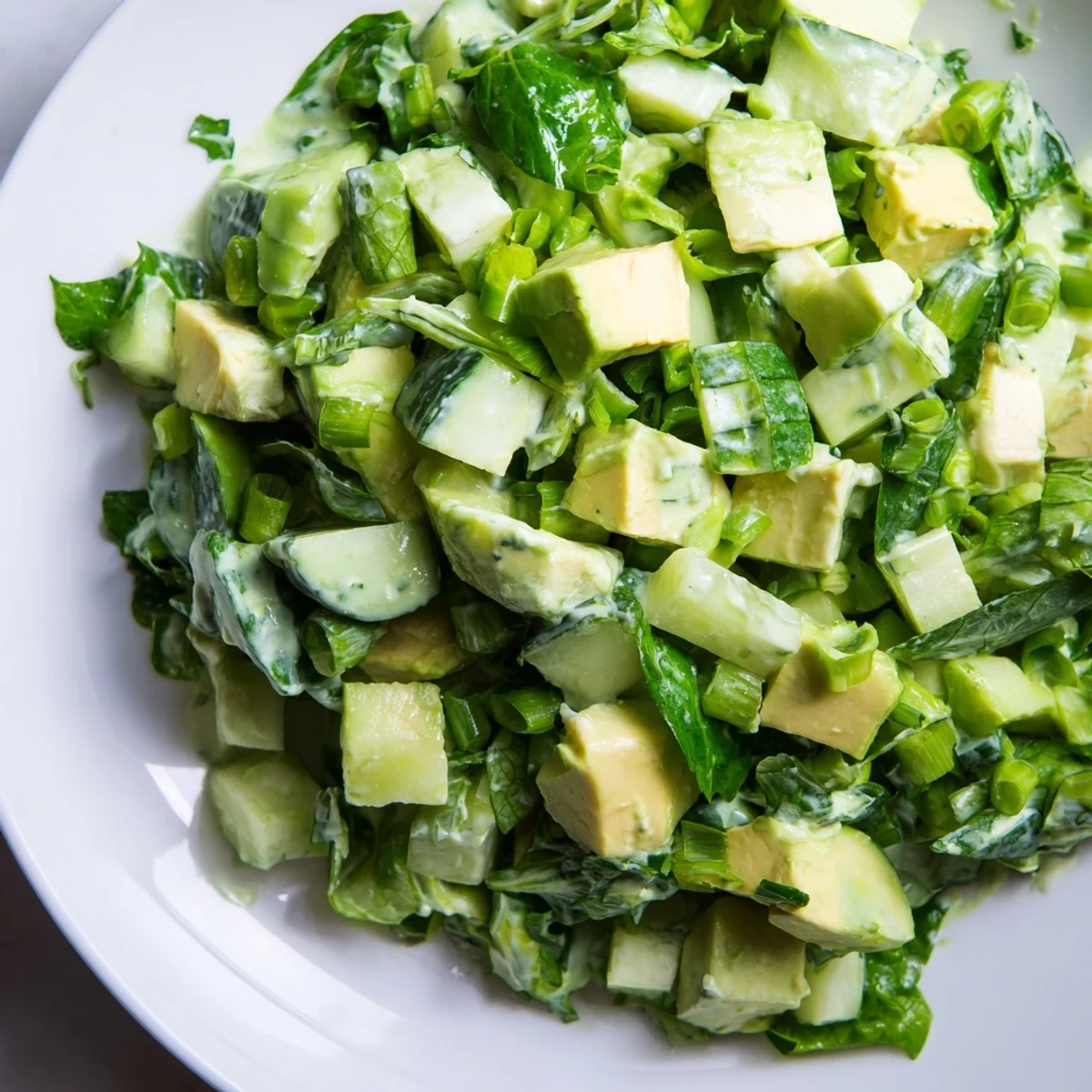 Creamy avocado chunks and crisp cucumber pieces glisten in the Green Goddess Salad with Avocado and Cucumber, tossed in vibrant green dressing.