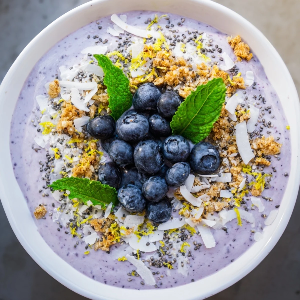 A vibrant Lemon Blueberry Smoothie Bowl topped with fresh berries, crunchy granola, and coconut flakes.