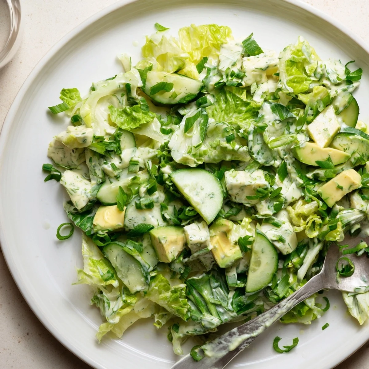 Overhead view of Green Goddess Salad with Avocado and bright dressing, plated with crusty bread on the side for dipping.