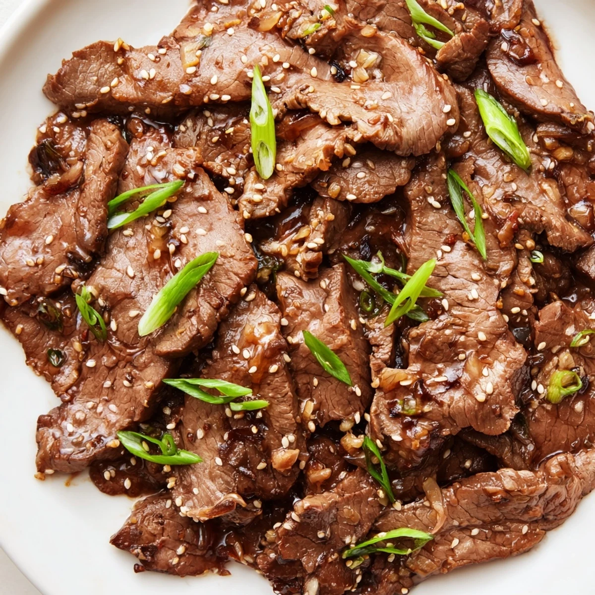 A close-up of Ultimate Slow Cooker Mongolian Beef showcases tender beef slices coated in a glossy, savory-sweet glaze.