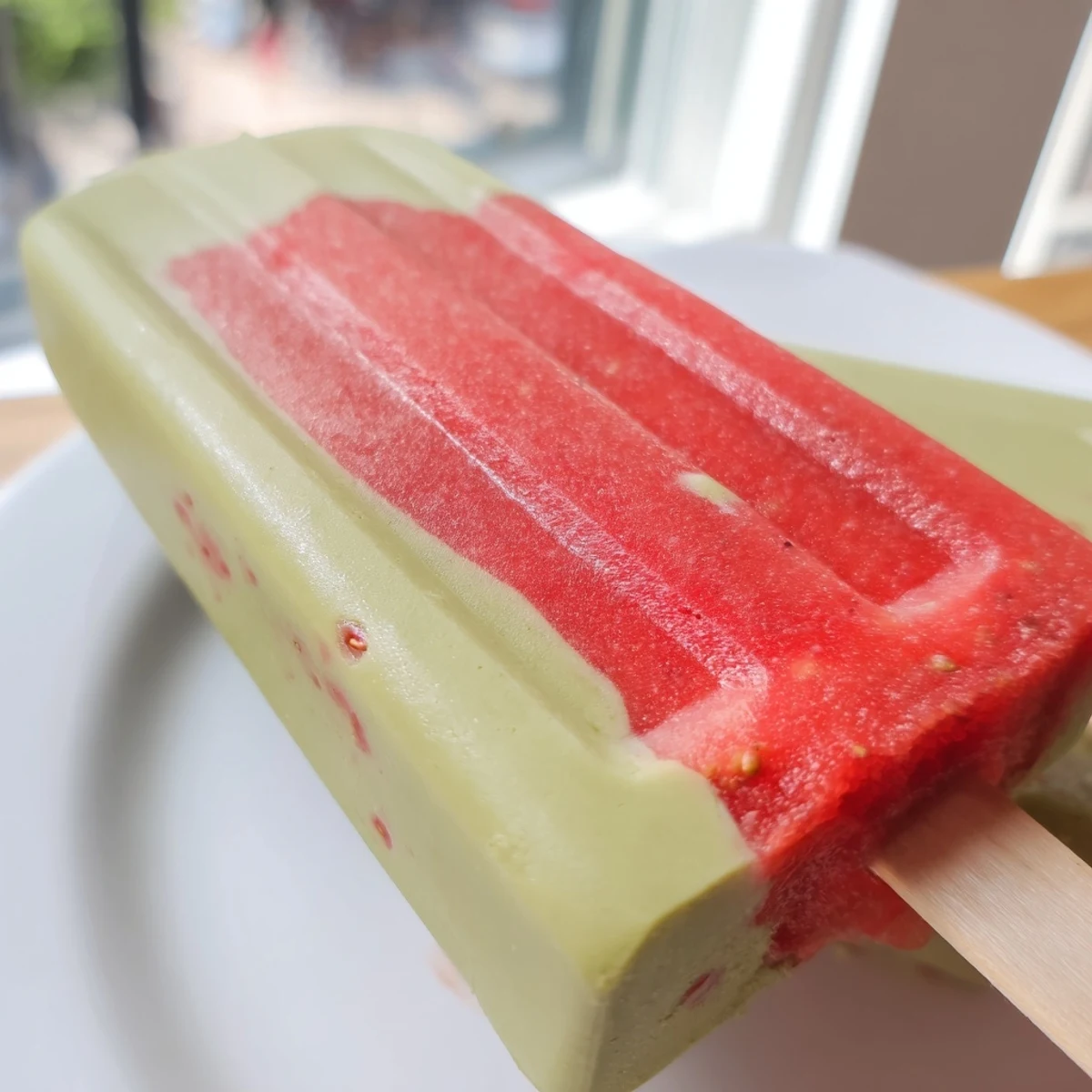Homemade Strawberry Matcha Latte Popsicles releasing from molds, showing creamy matcha and strawberry textures.