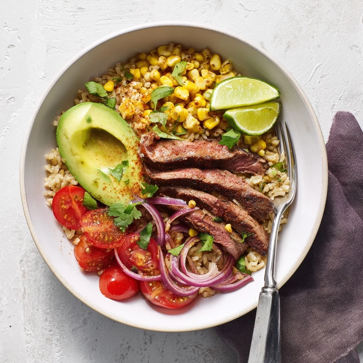 Juicy steak and vibrant roasted corn sit atop quinoa in a tempting Steak Avocado Roasted Corn Bowl.
