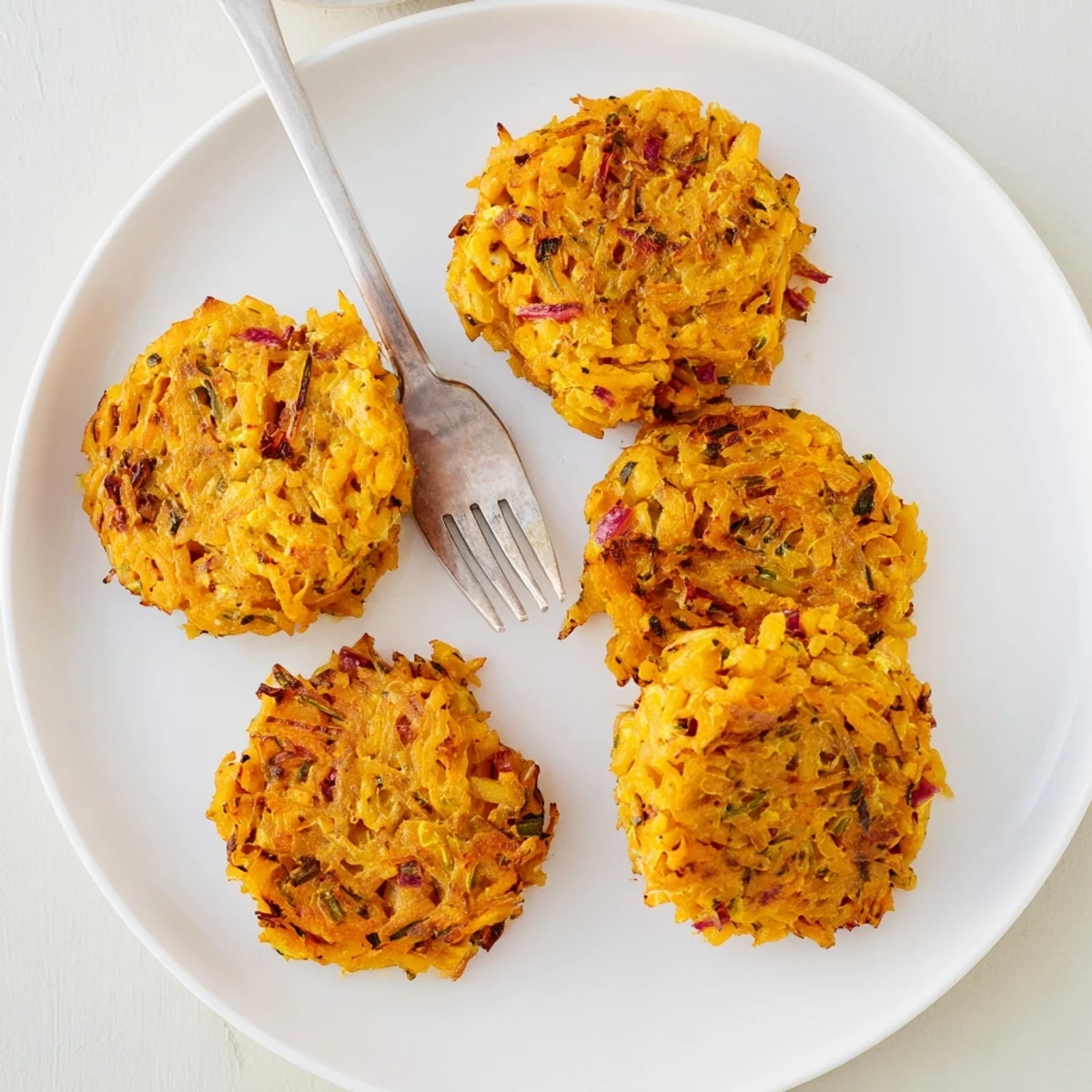 Golden baked Healthy Sweet Potato Hash Browns patties sit crisp on a parchment-lined tray, ready for brunch or as a light vegetarian side dish.