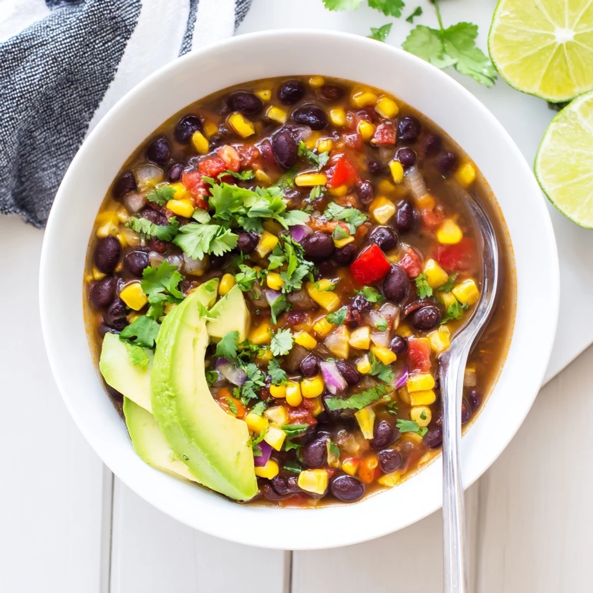Close-up of Black Bean Corn Chili Lime Delight served with lime wedges on the side.