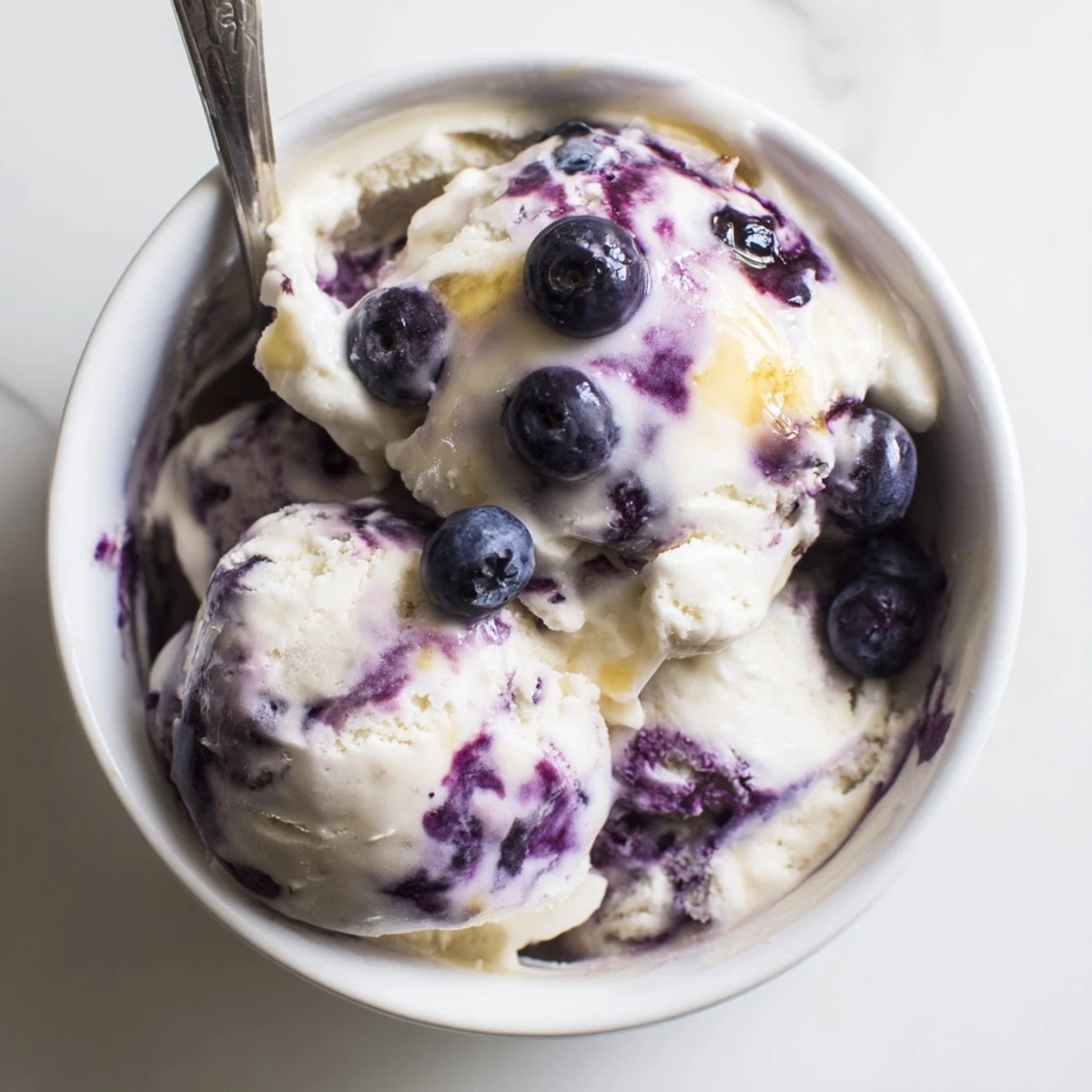 A serving of Blueberry Cottage Cheese Ice Cream in a glass dish, garnished with mint leaves for a refreshing summer dessert.