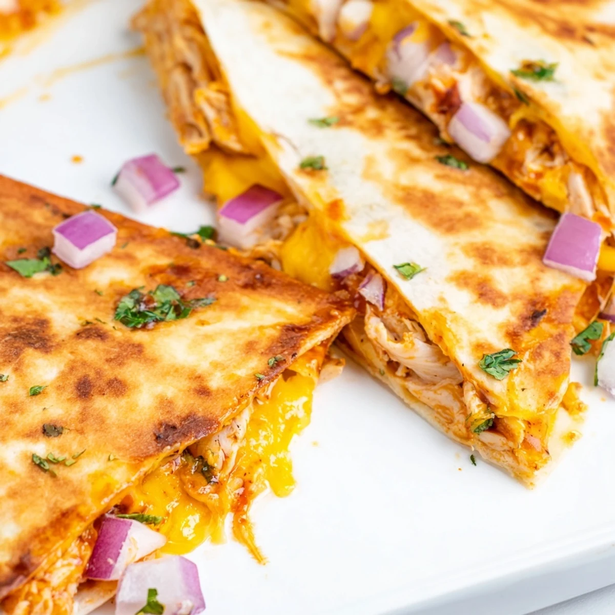 Warm wedges of Hot Honey BBQ Chicken Quesadillas served with lime wedges and a dollop of sour cream.