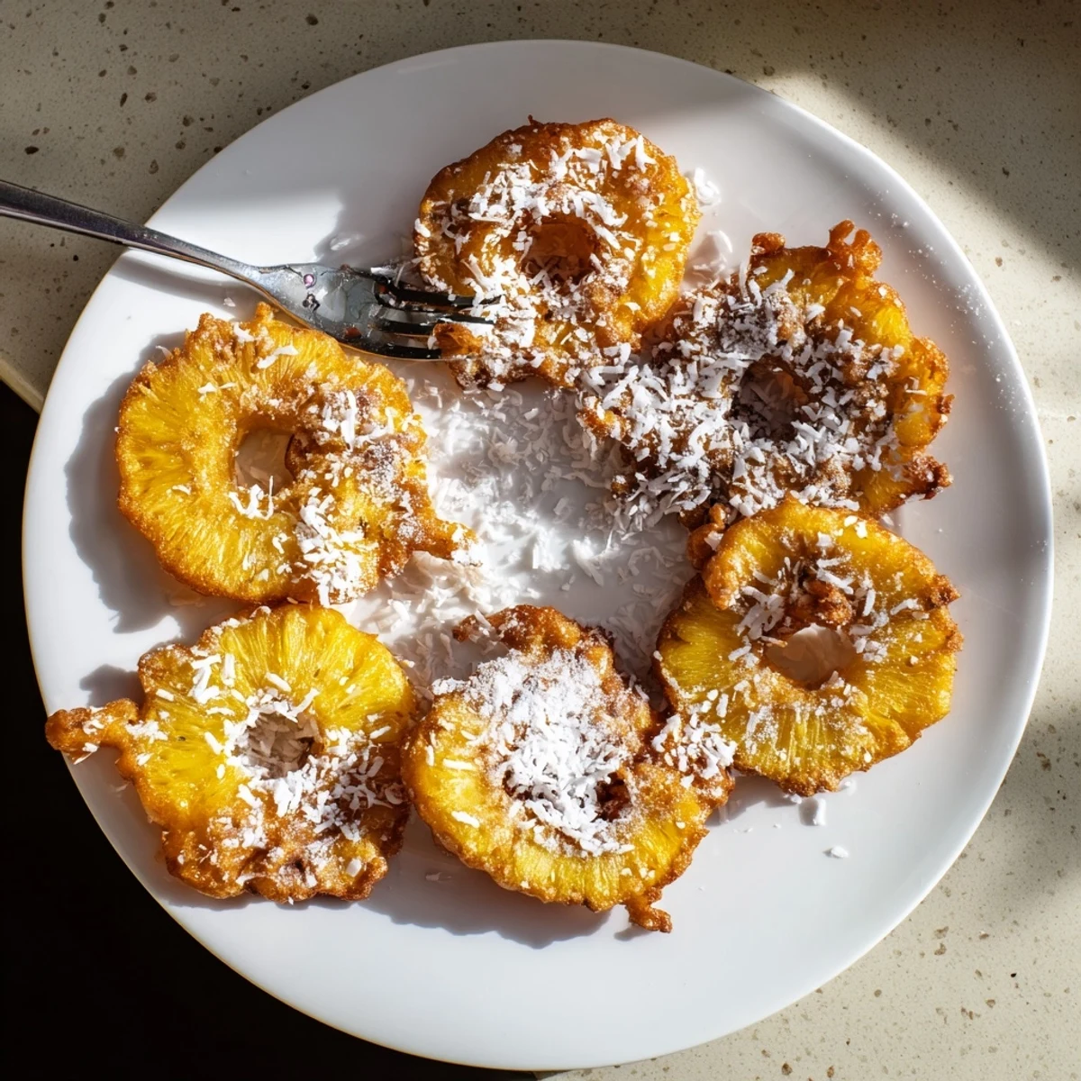 Warm tropical pineapple fritters with toasted coconut garnish ready for dessert serving.