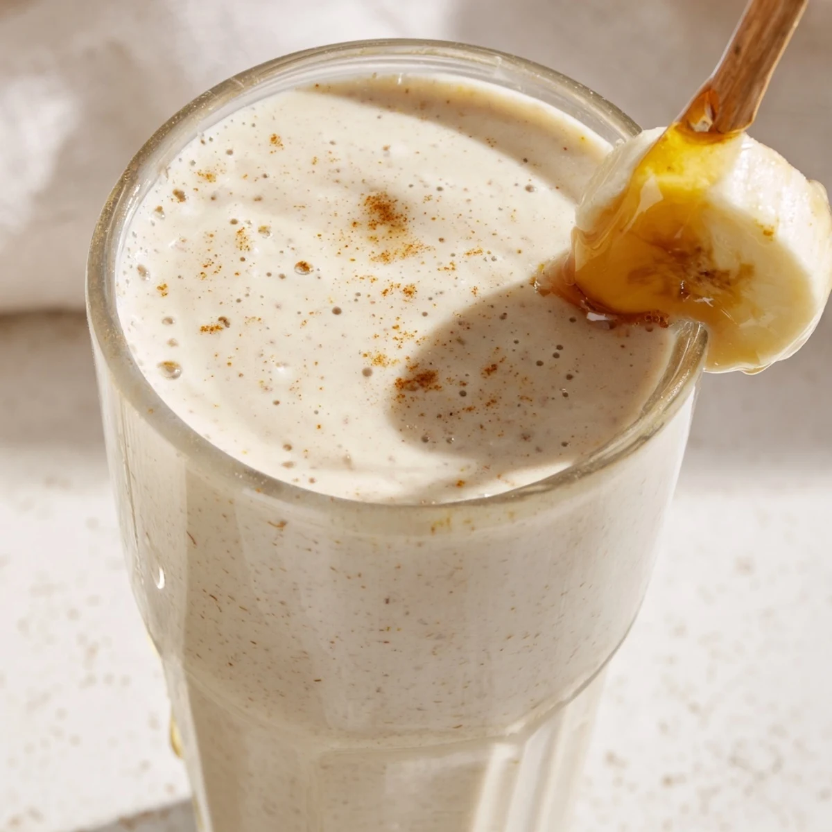 Refreshing Greek yogurt banana smoothie blended with ice and served in tall glass glasses