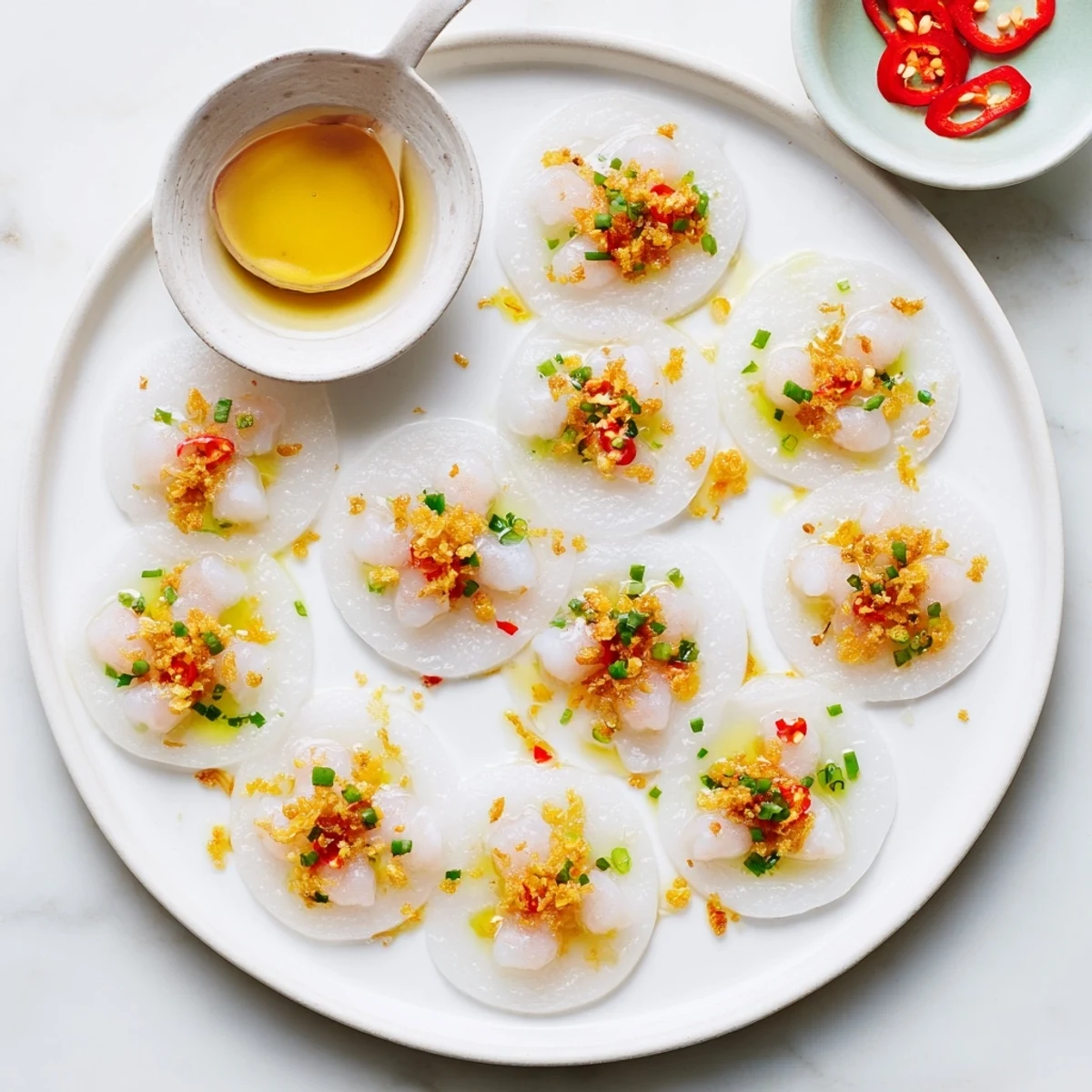 Small white Banh Beo Vietnamese cakes garnished with golden shrimp and fragrant green onion oil