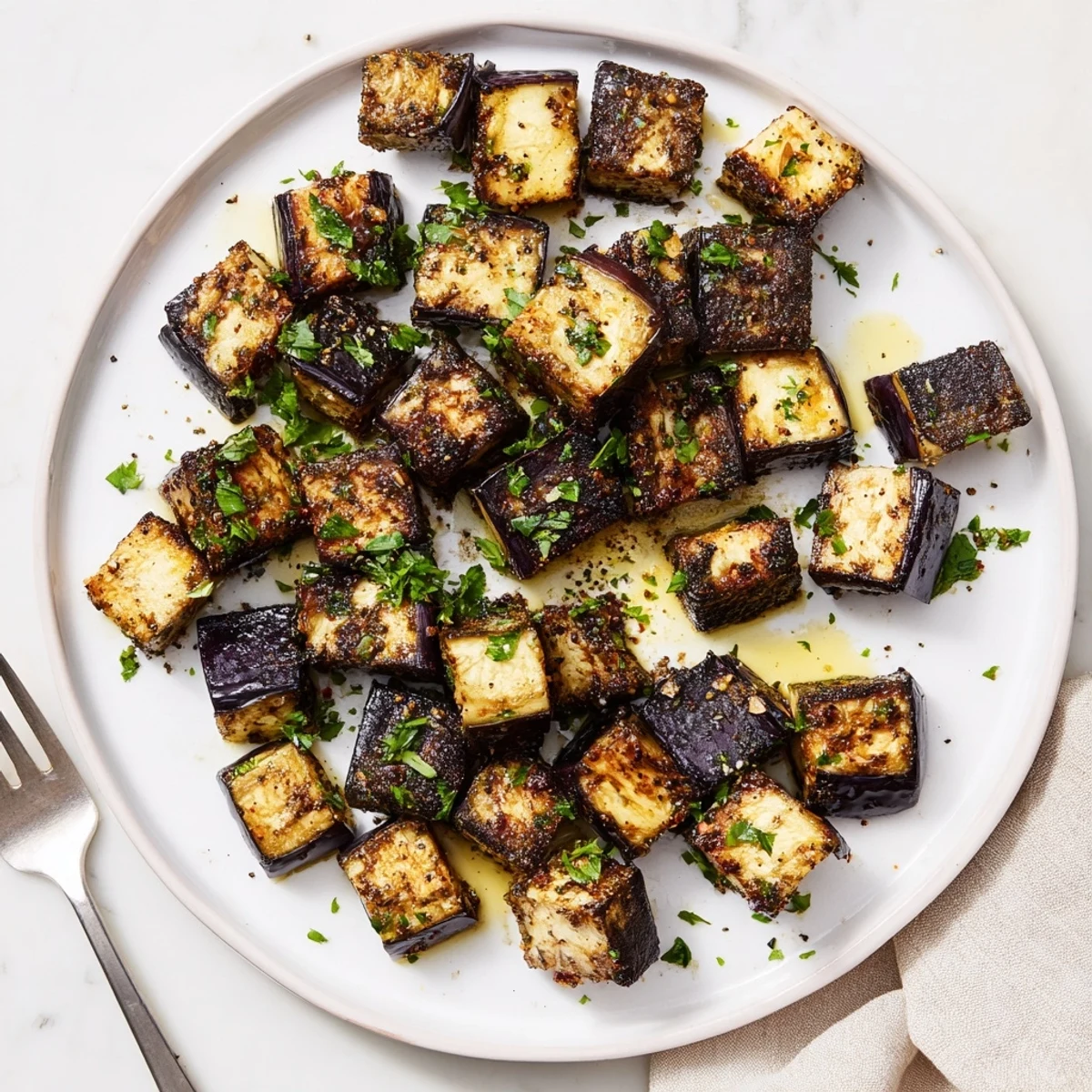 Crispy low calorie air fryer eggplant pieces arranged on white plate with lemon wedge