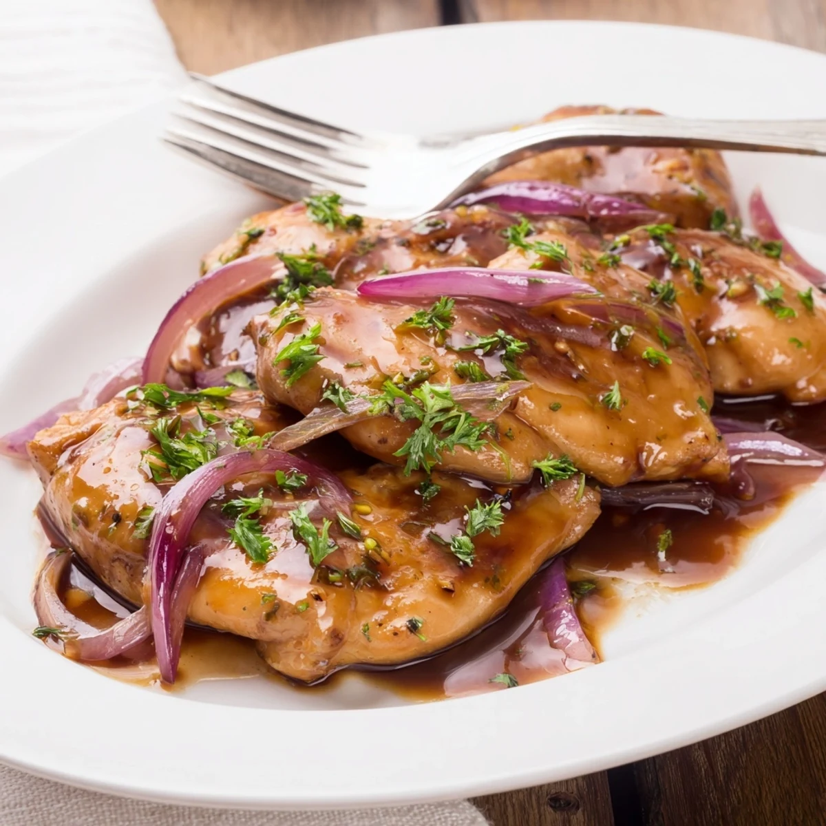 Savory slow cooker balsamic chicken with caramelized onion and honey mustard reduction on a white plate