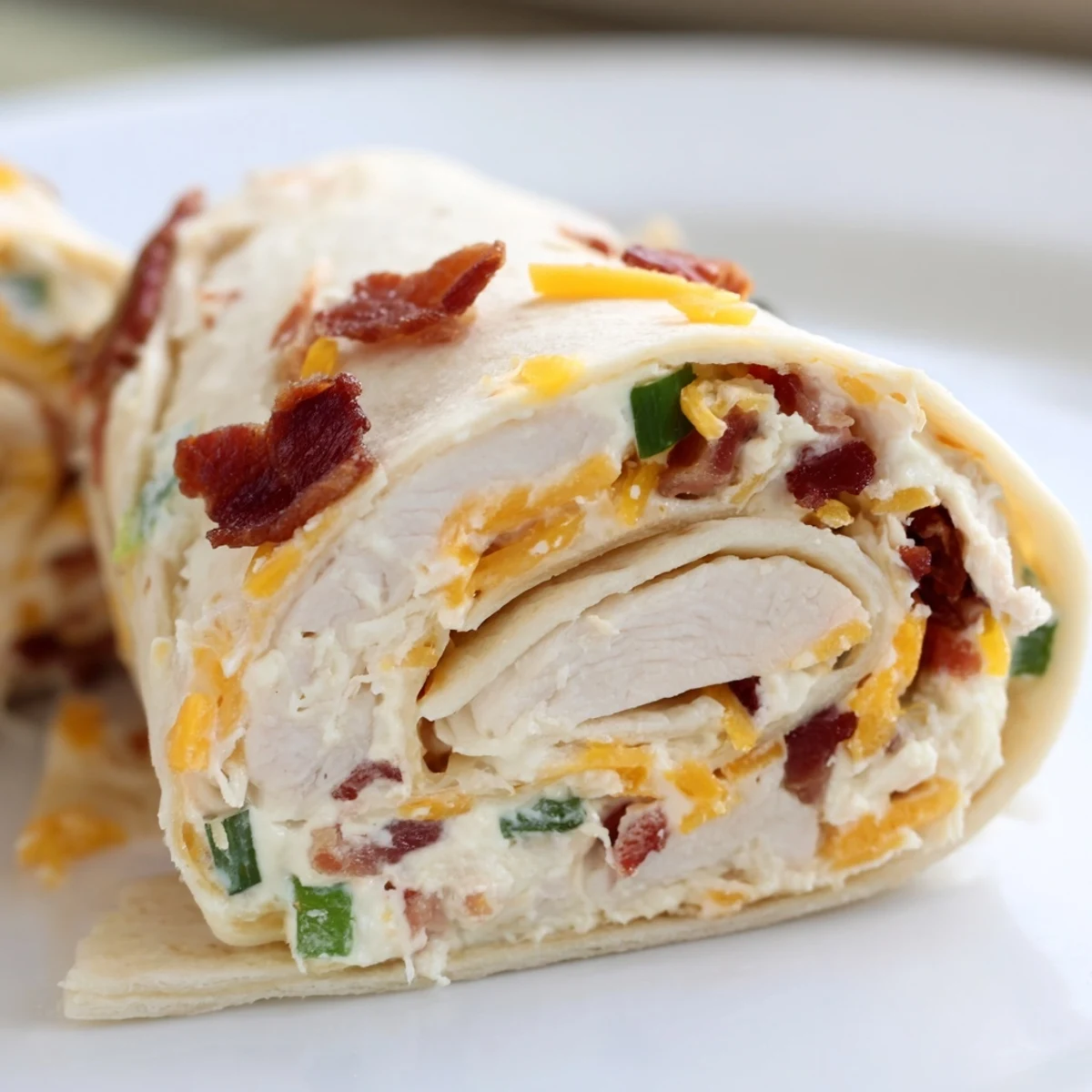 Party ready crack chicken pinwheels arranged on white serving platter with green onion garnish