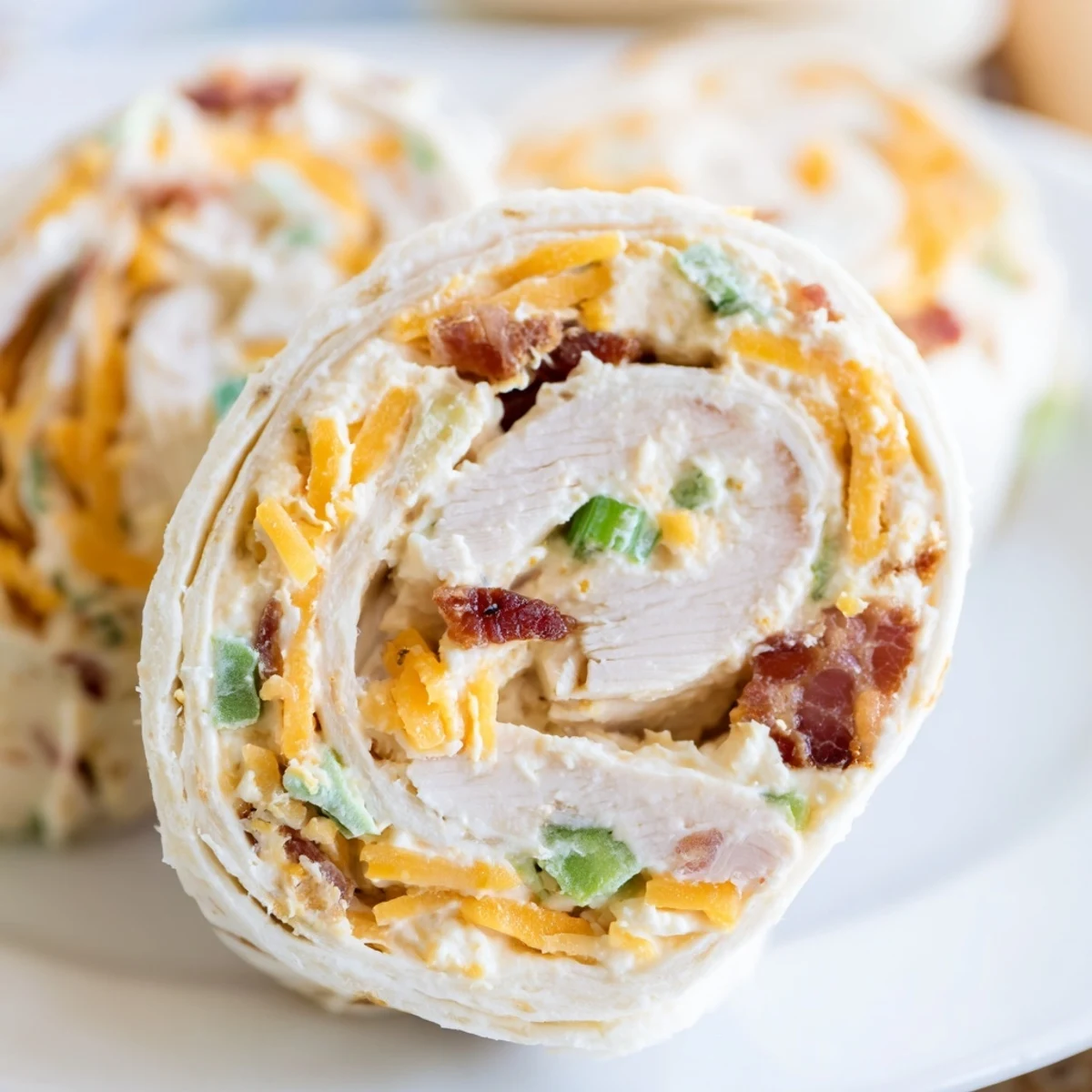 Close up of crack chicken pinwheels showing layers of cheese, bacon, and seasoned chicken filling