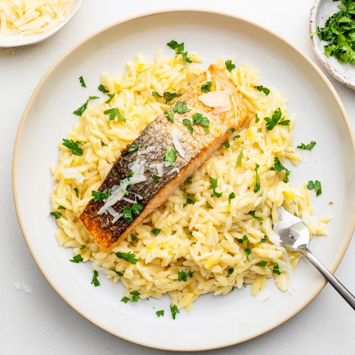 Mediterranean style salmon nestled atop zesty orzo pasta in a single golden pan
