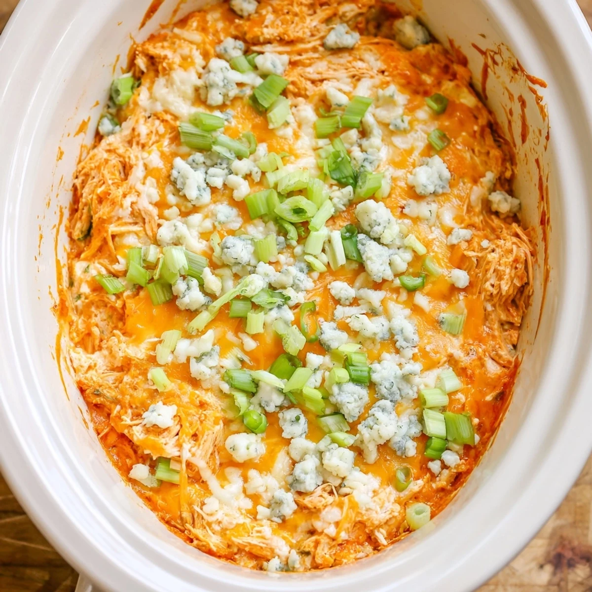 Creamy Crockpot Buffalo Chicken Dip bubbling with melted cheddar and mozzarella cheese topped with fresh chives