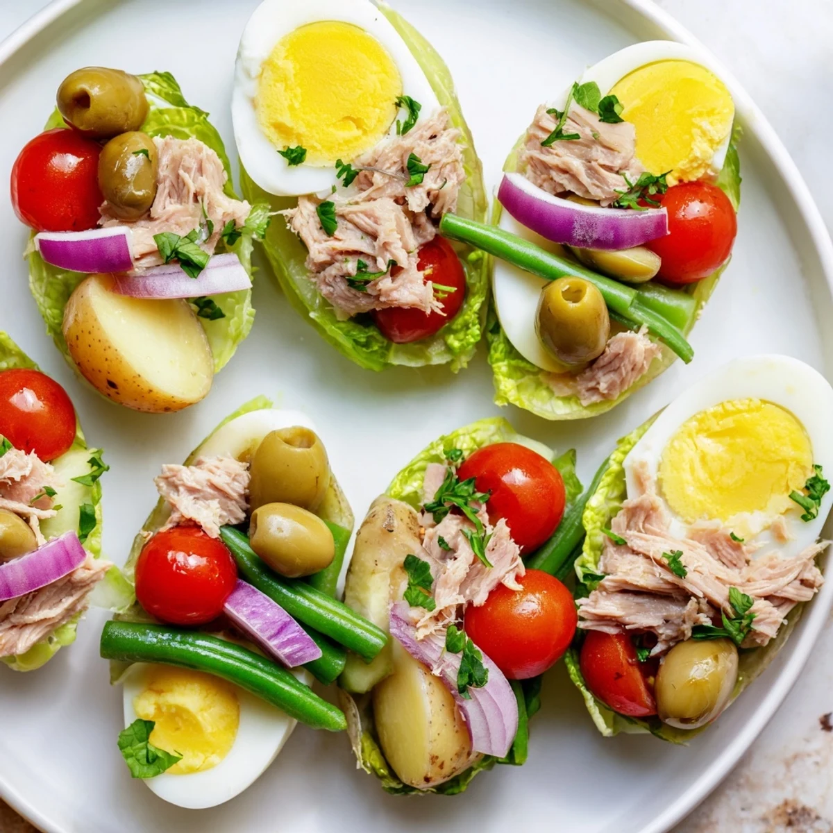Colorful Classic Niçoise Salad arranged on a white platter with tuna, eggs, and fresh vegetables