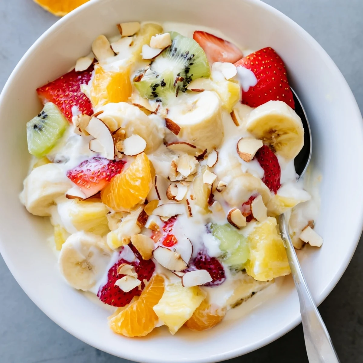 Refreshing creamy fruit salad with tropical fruit chunks drizzled with sweet honey cream dressing and topped with toasted coconut flakes