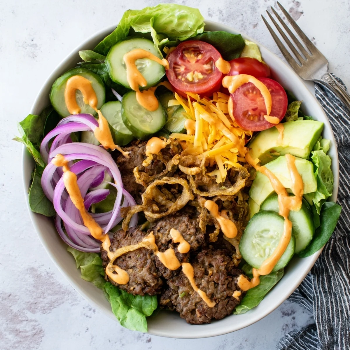 Colorful smash burger bowl featuring crispy seared beef patties over fresh salad greens with ripe avocado slices and cheddar cheese