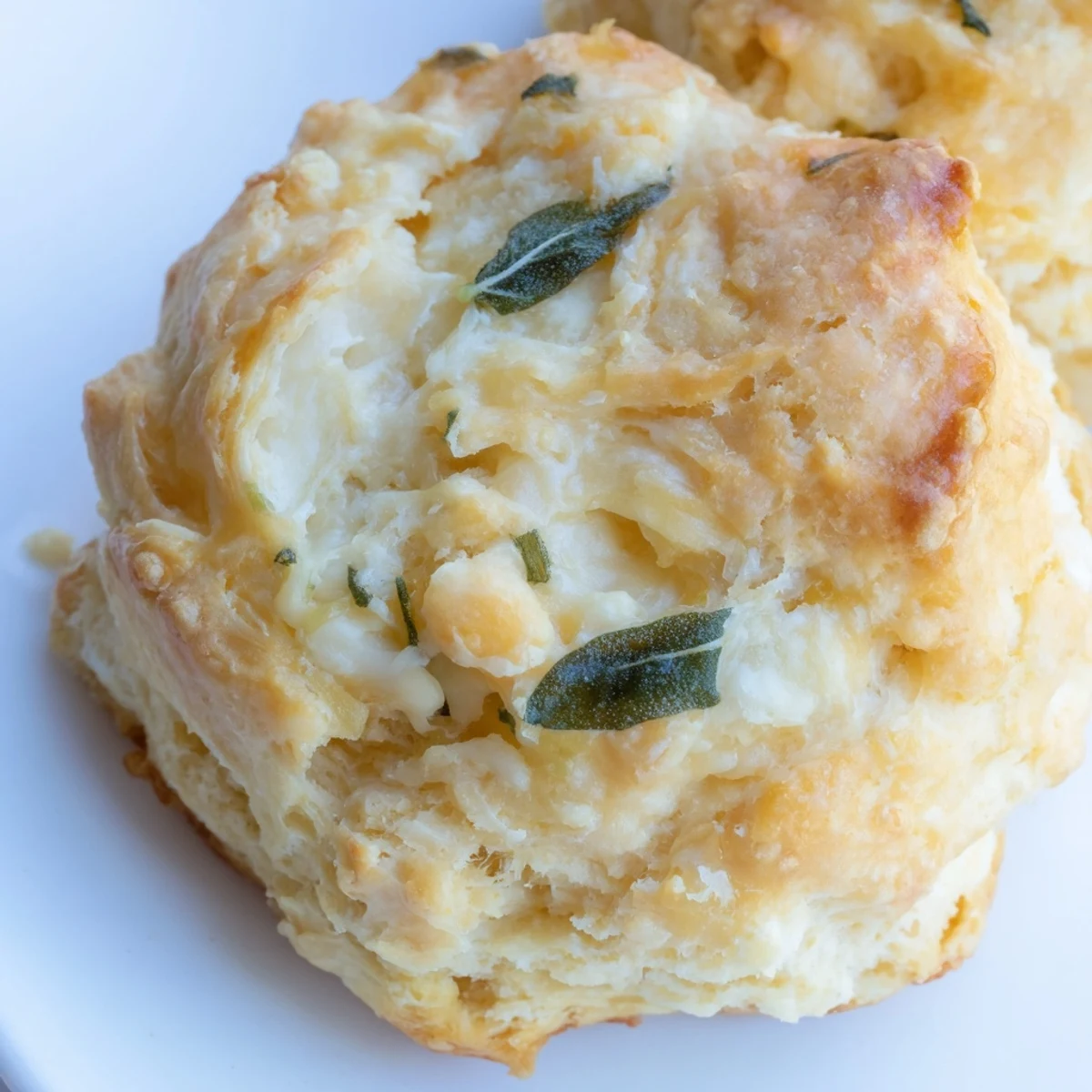 Golden brown sage and Gruyere biscuits stacked on a wooden cutting board ready for serving