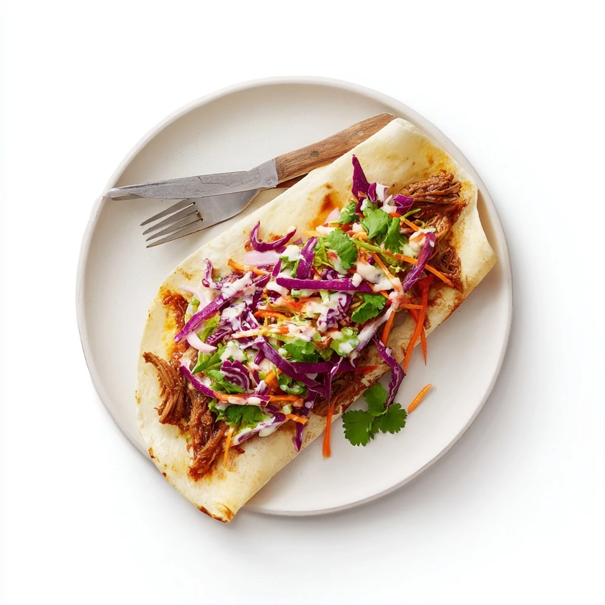 Tender BBQ pulled beef wrapped in flour tortillas topped with colorful crunchy cabbage slaw