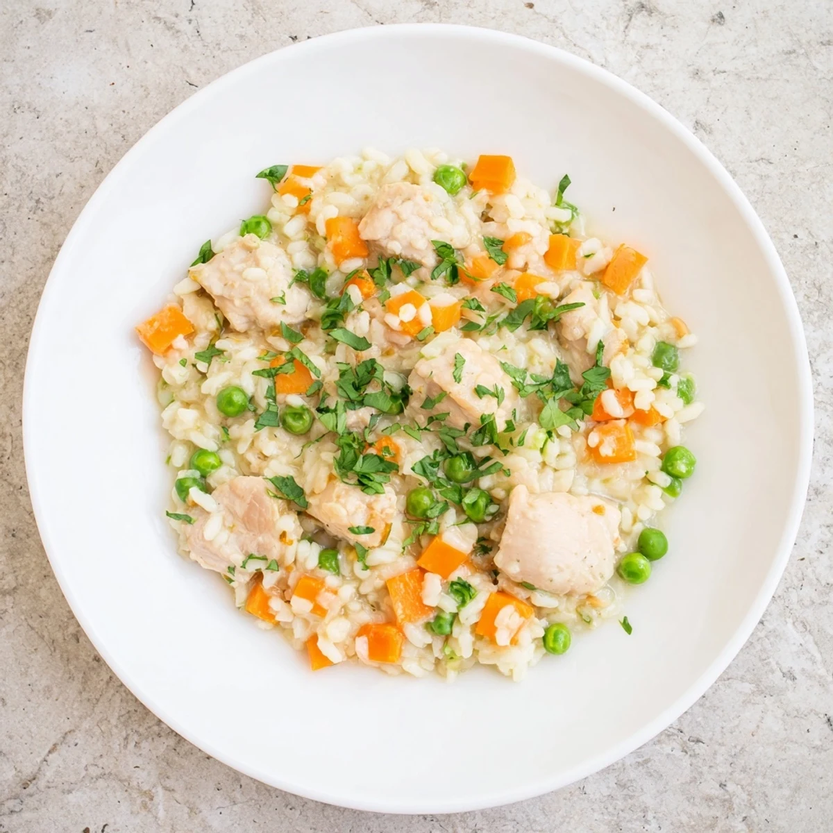 Golden chicken and peas nestled in fluffy white rice, garnished with fresh parsley in a serving bowl