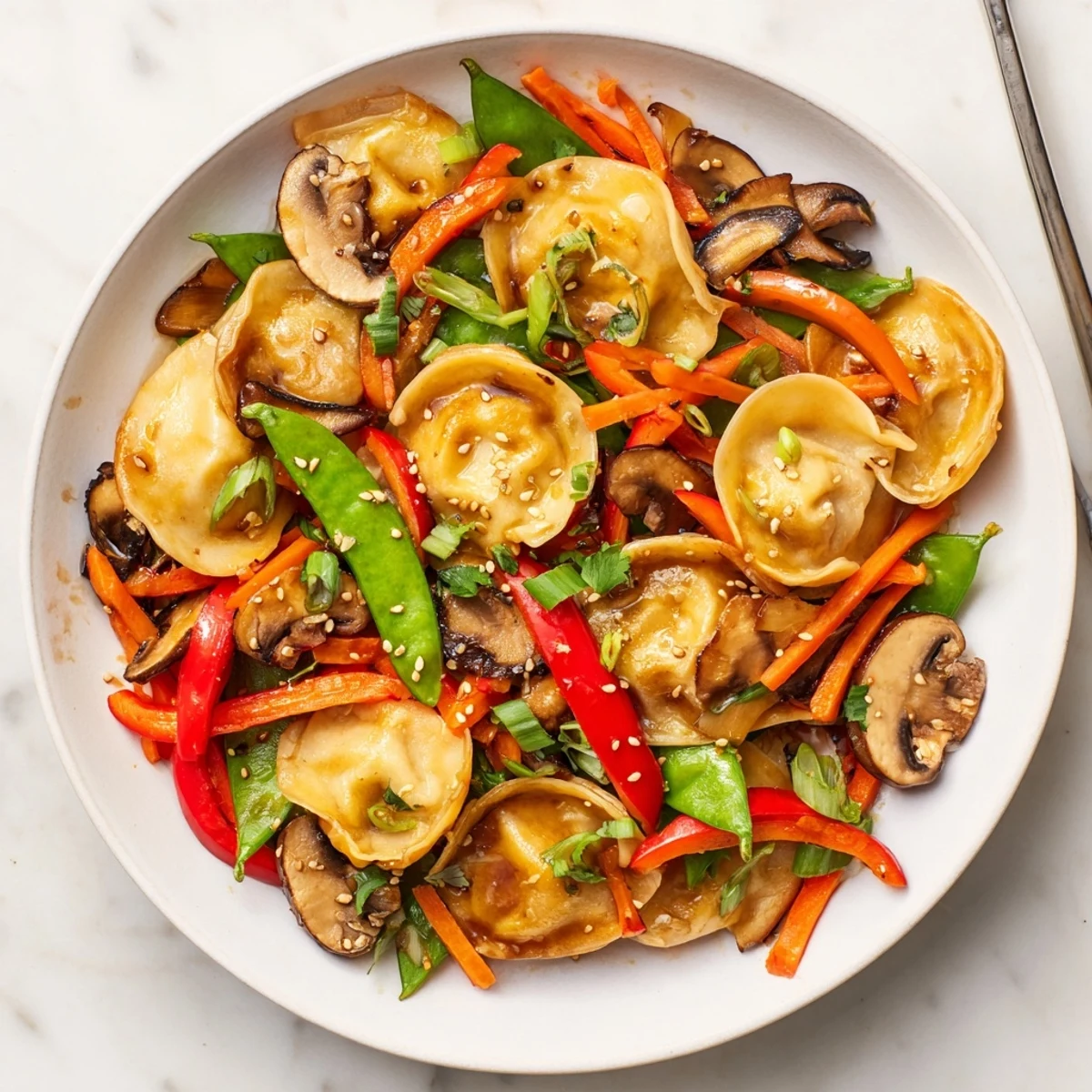 Crispy pan-fried potstickers tossed with fresh vegetables and sesame garnish in a wok