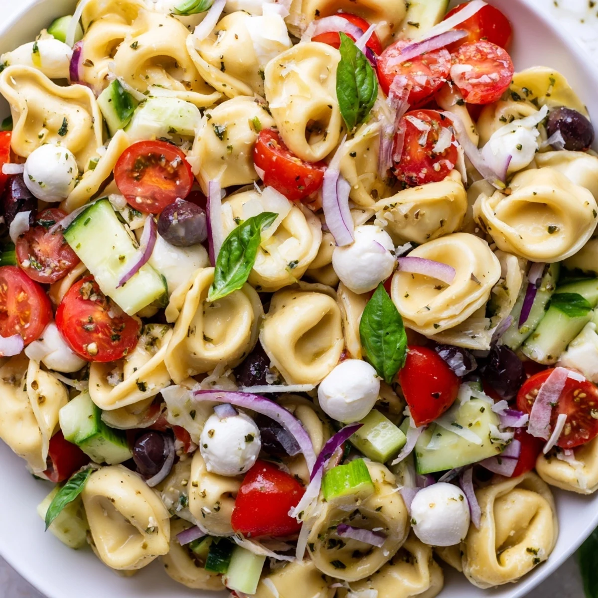 Creamy cheese tortellini tossed with crisp vegetables and zesty Italian dressing in a serving bowl