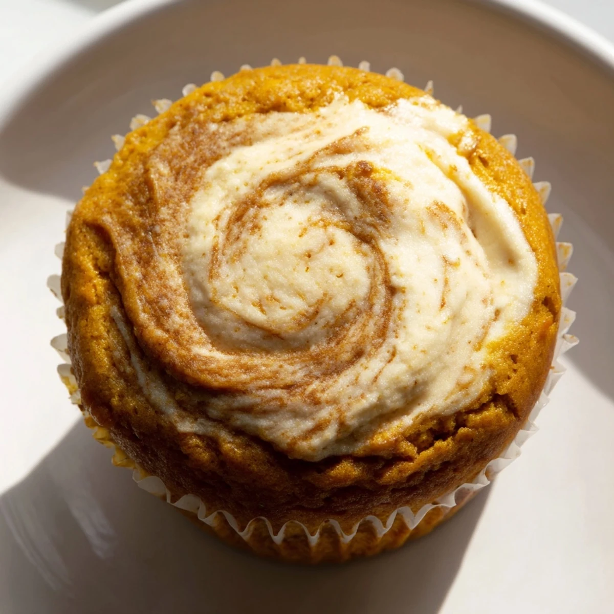 Golden chai pumpkin cheesecake muffins with swirled spiced cream cheese filling on rustic parchment