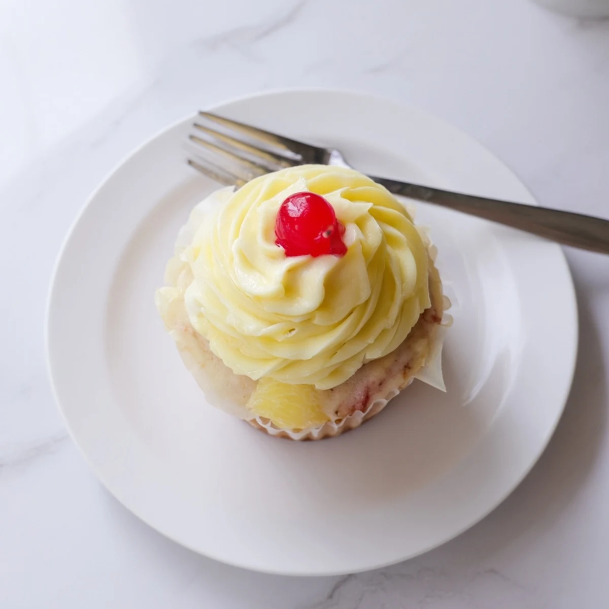 A tray of freshly baked Dole Whip Cupcakes with fluffy pineapple cream and pineapple wedges