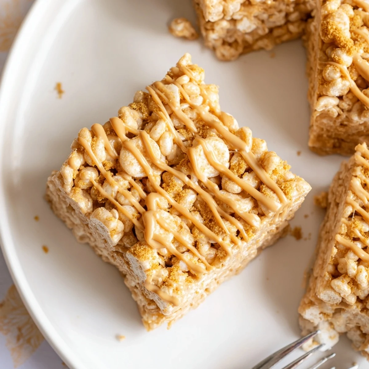 Biscoff Rice Krispie Treats stacked, glossy Biscoff drizzle, crunchy caramelized bites