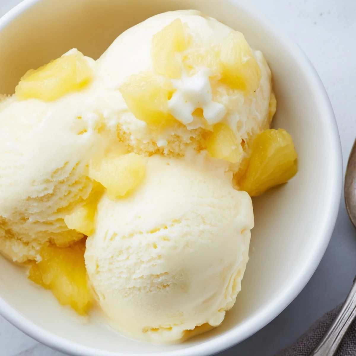 Chilled Creamy Pineapple Ice Cream with visible pineapple pieces, silky mouthfeel.