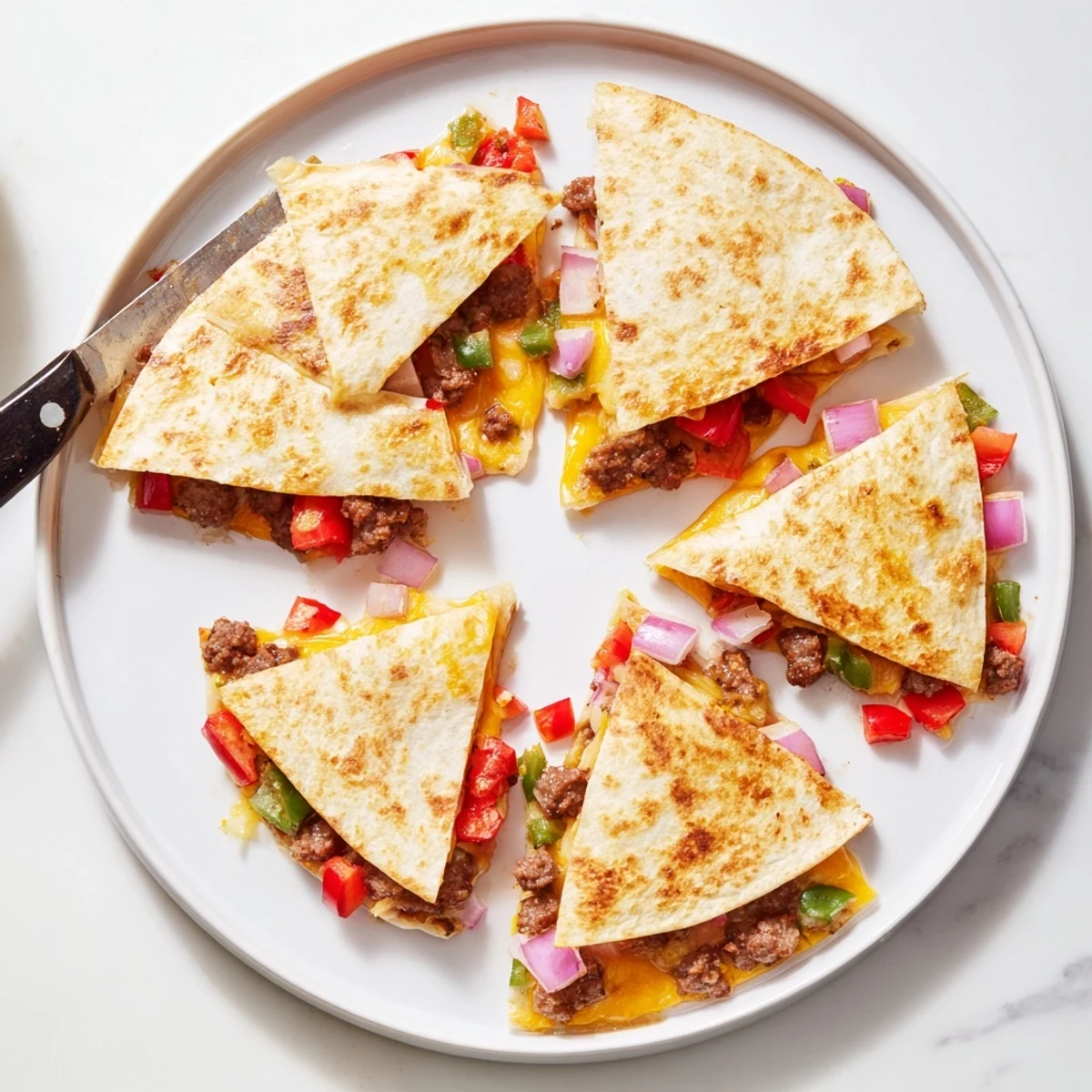 Cut quesadilla wedges revealing spicy beef sausage and melty cheese between crispy golden tortillas