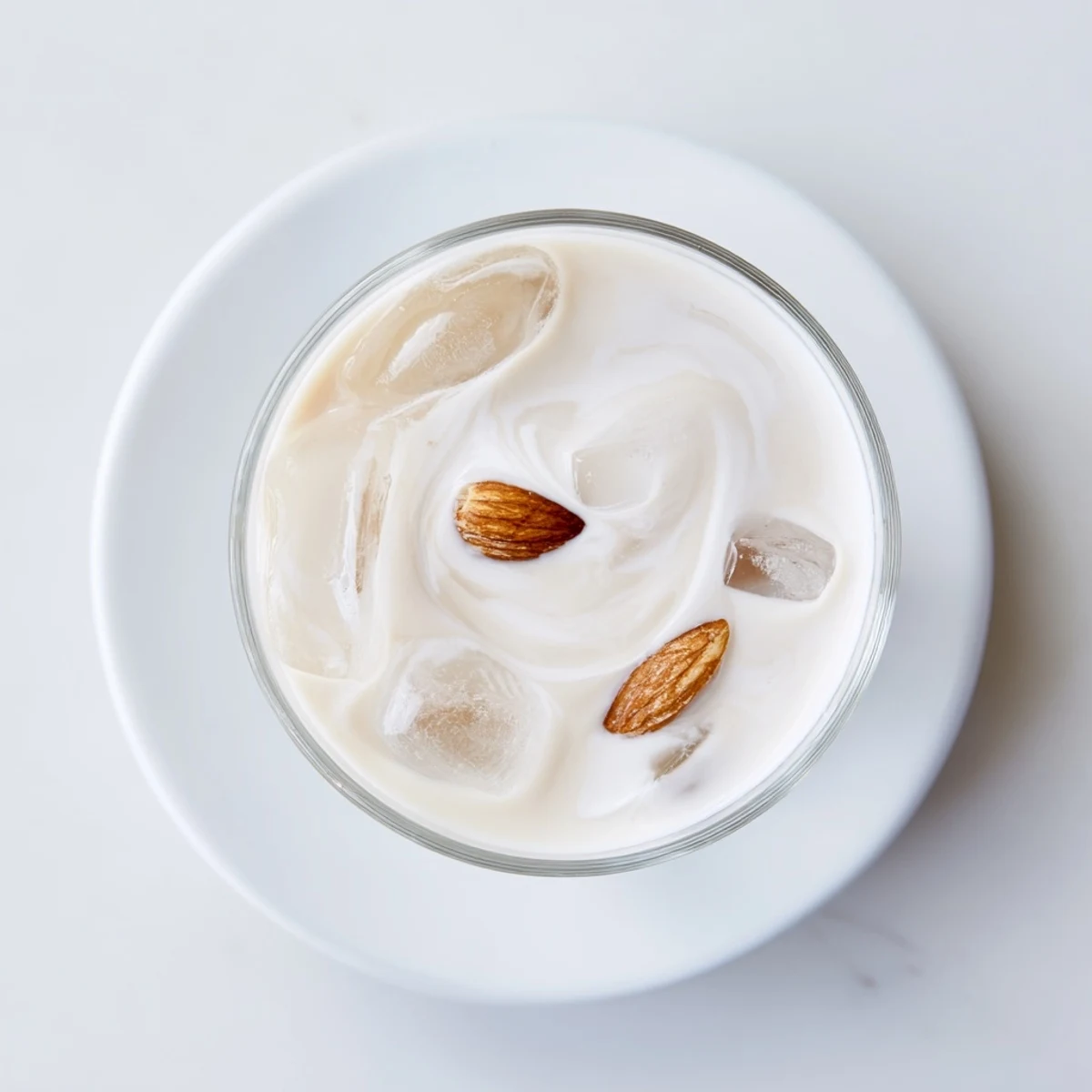 Golden roasted almond milk drink topped with cream and ice cubes in a chilled glass