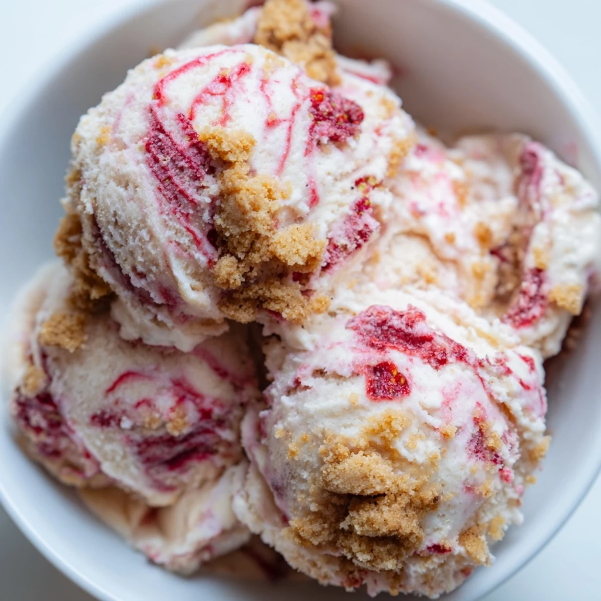 Homemade strawberry cheesecake ice cream topped with fresh strawberry compote and buttery crumbled graham crackers