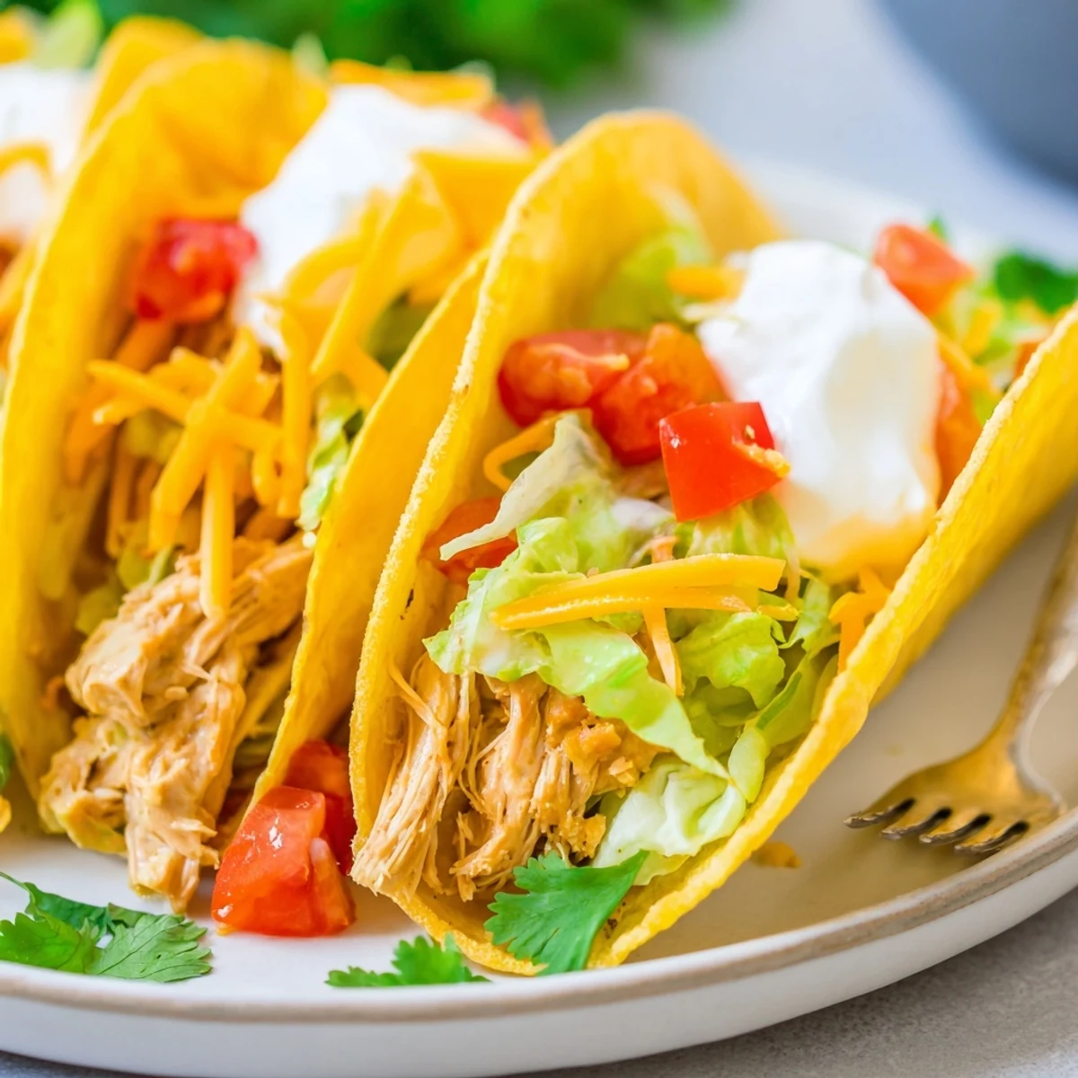 Shredded slow cooker ranch chicken tacos loaded with sour cream and crisp lettuce