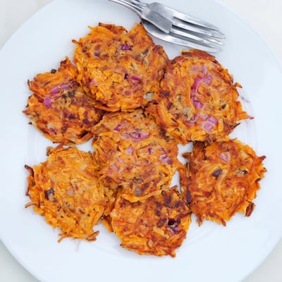 A close-up shows seasoned Healthy Sweet Potato Hash Browns with a tender orange interior, topped with fresh sliced green onions for extra color.
